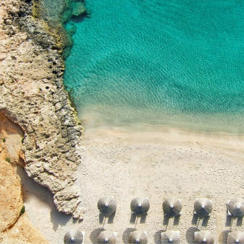 Eine Luftaufnahme eines Strandes mit Sonnenschirmen und Stühlen.