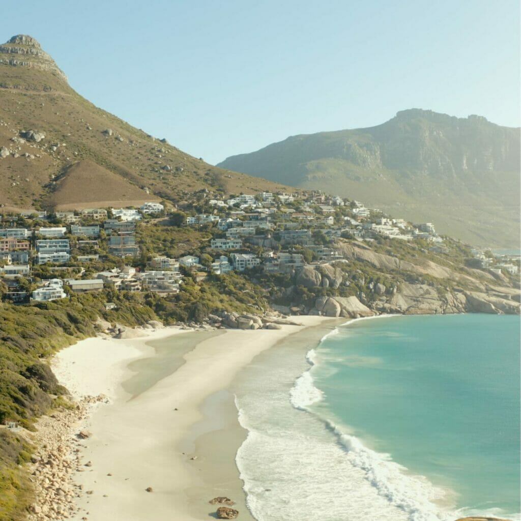 Ein Strand in Kapstadt mit Bergen im Hintergrund.